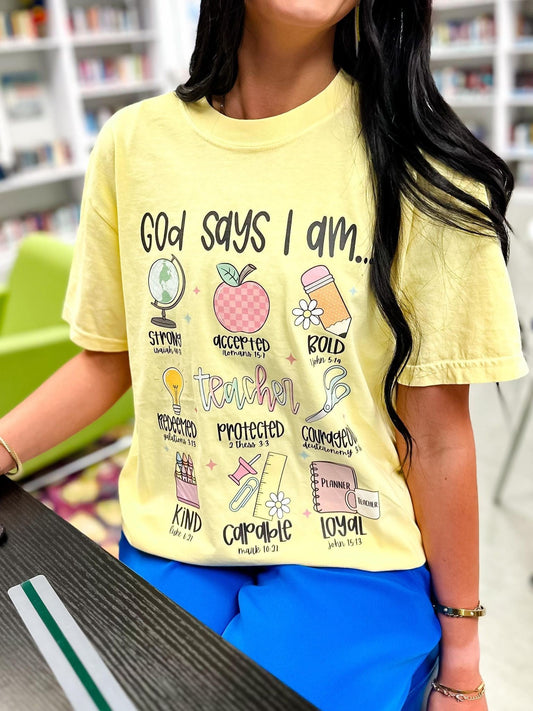 Person wearing a butter yellow t-shirt with Teacher God says I am motivational phrases and graphics in a school setting