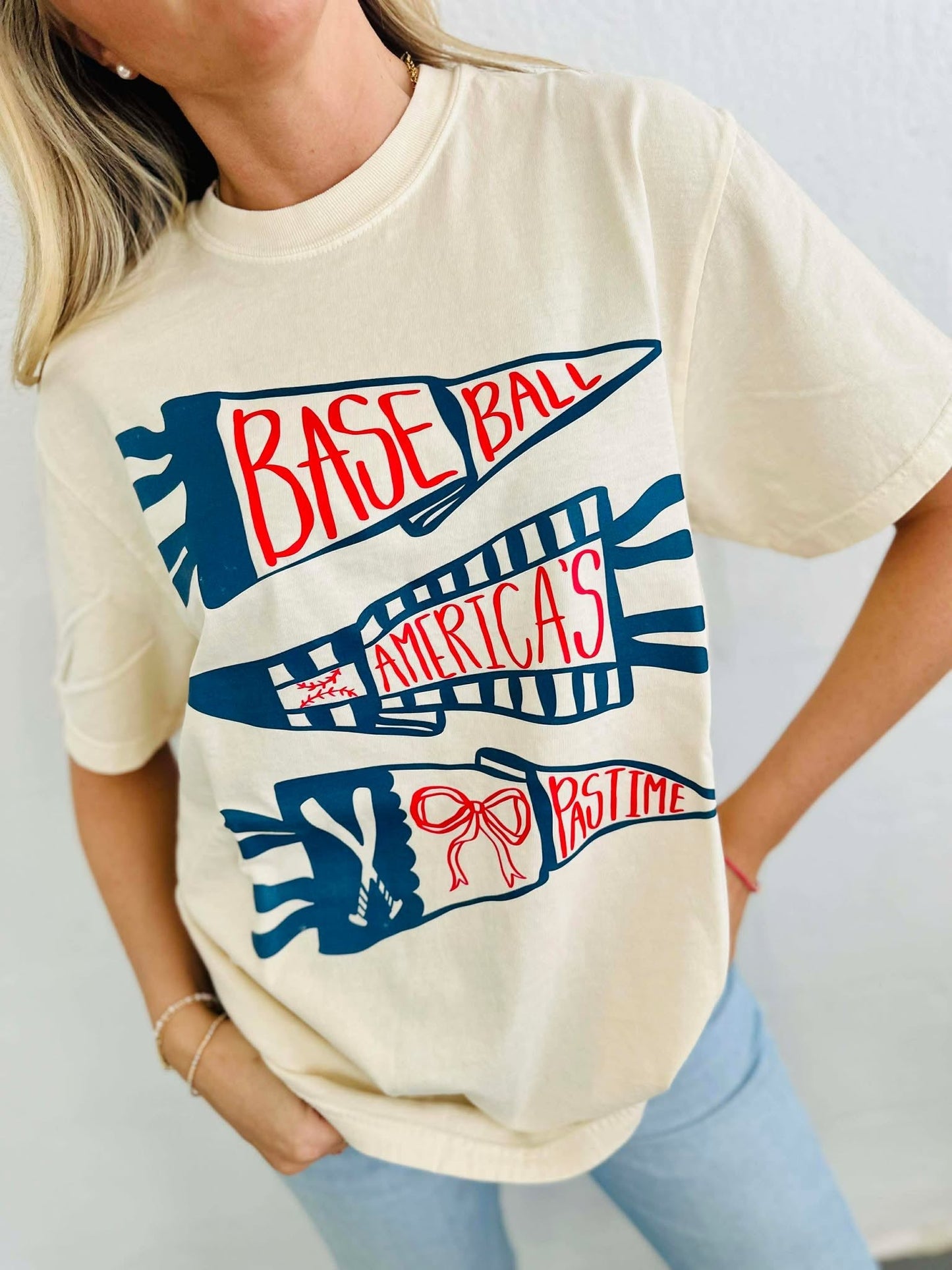 Person wearing a cream t-shirt with 'Baseball America's Pastime' graphic design.
