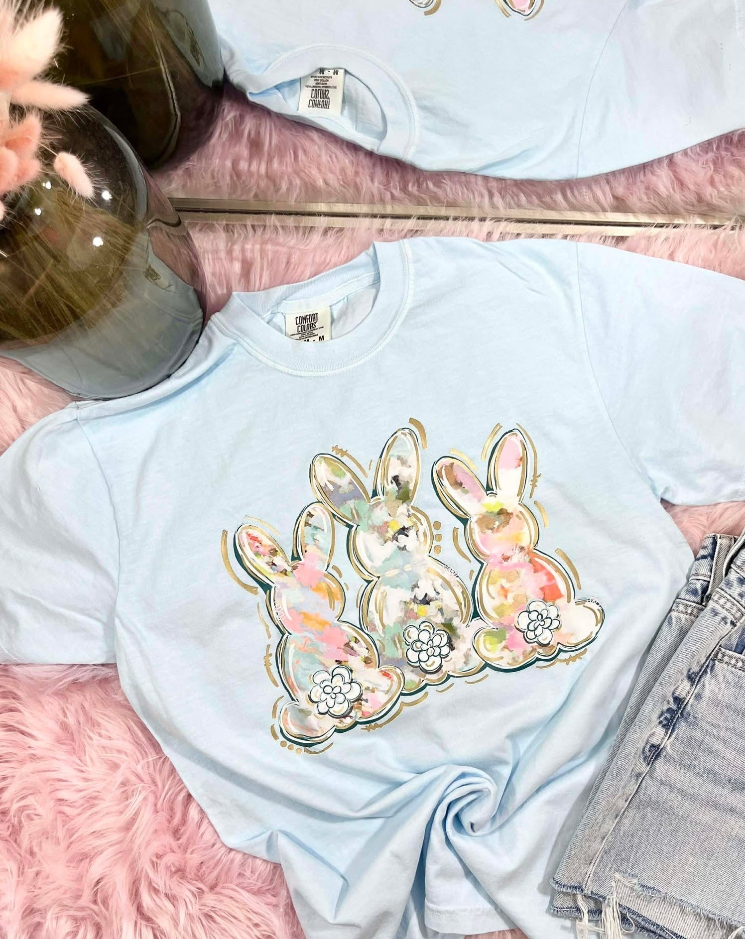 Light blue t-shirt with water color brushed floral bunny design on a pink surface